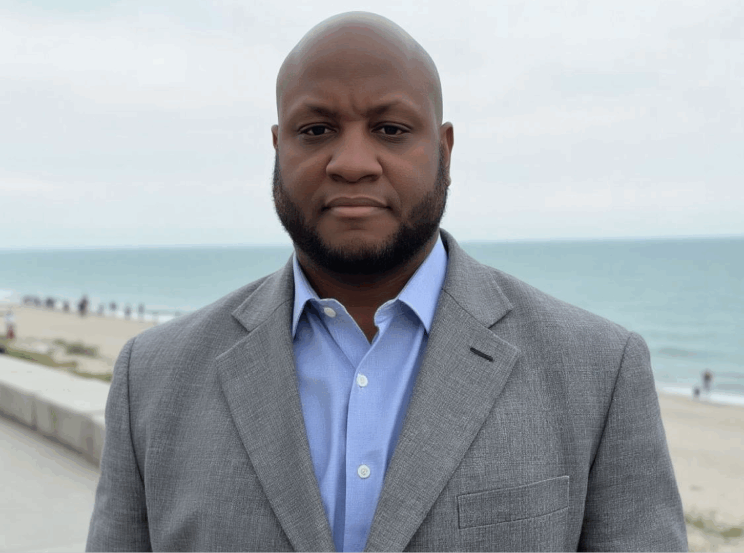 Man in suit standing by the beach.