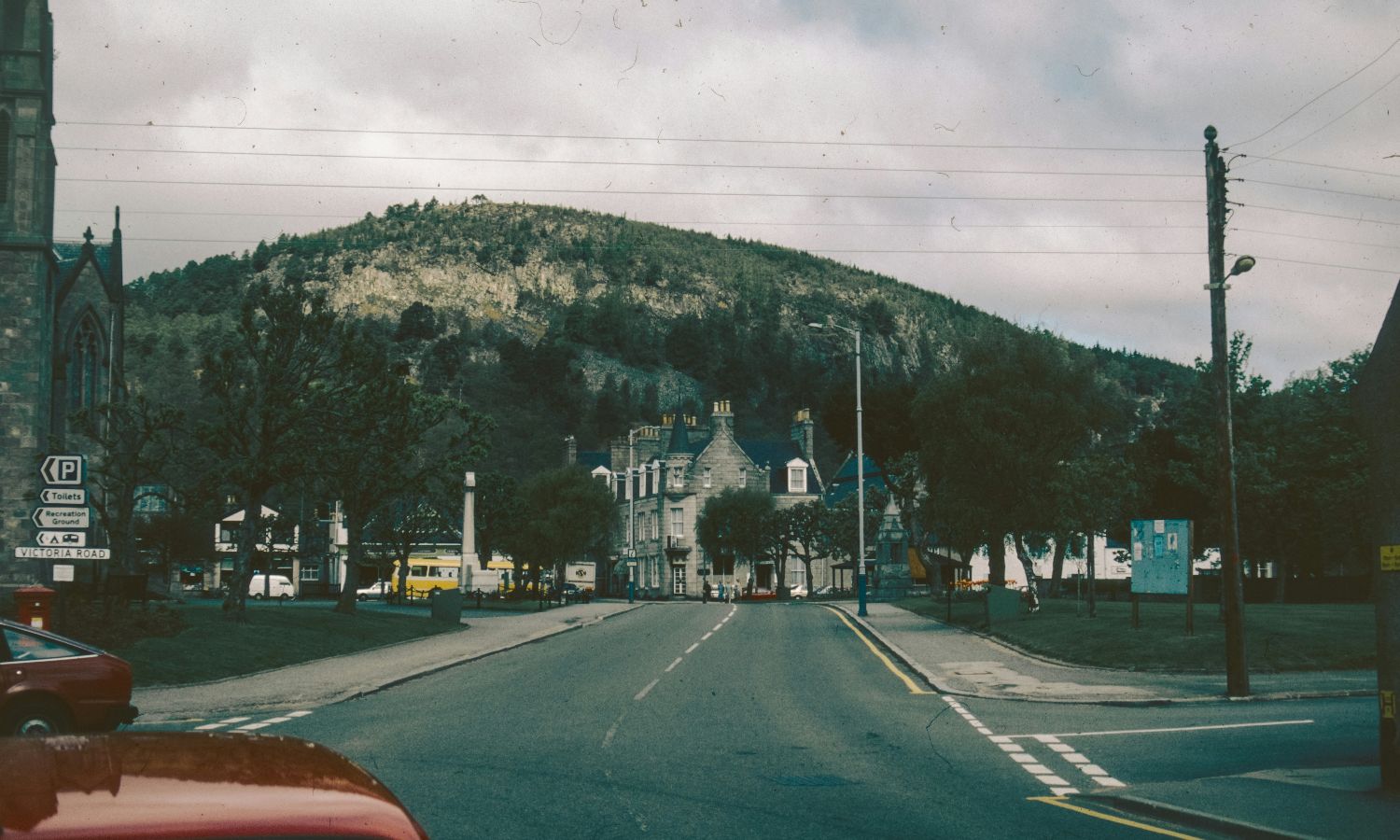 A road leading to a church with a mountain backdrop under a cloudy sky.
